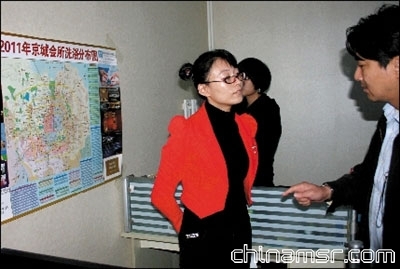 警员正在询问涉案公司的工作人员，墙上贴着洗浴场所分布图。